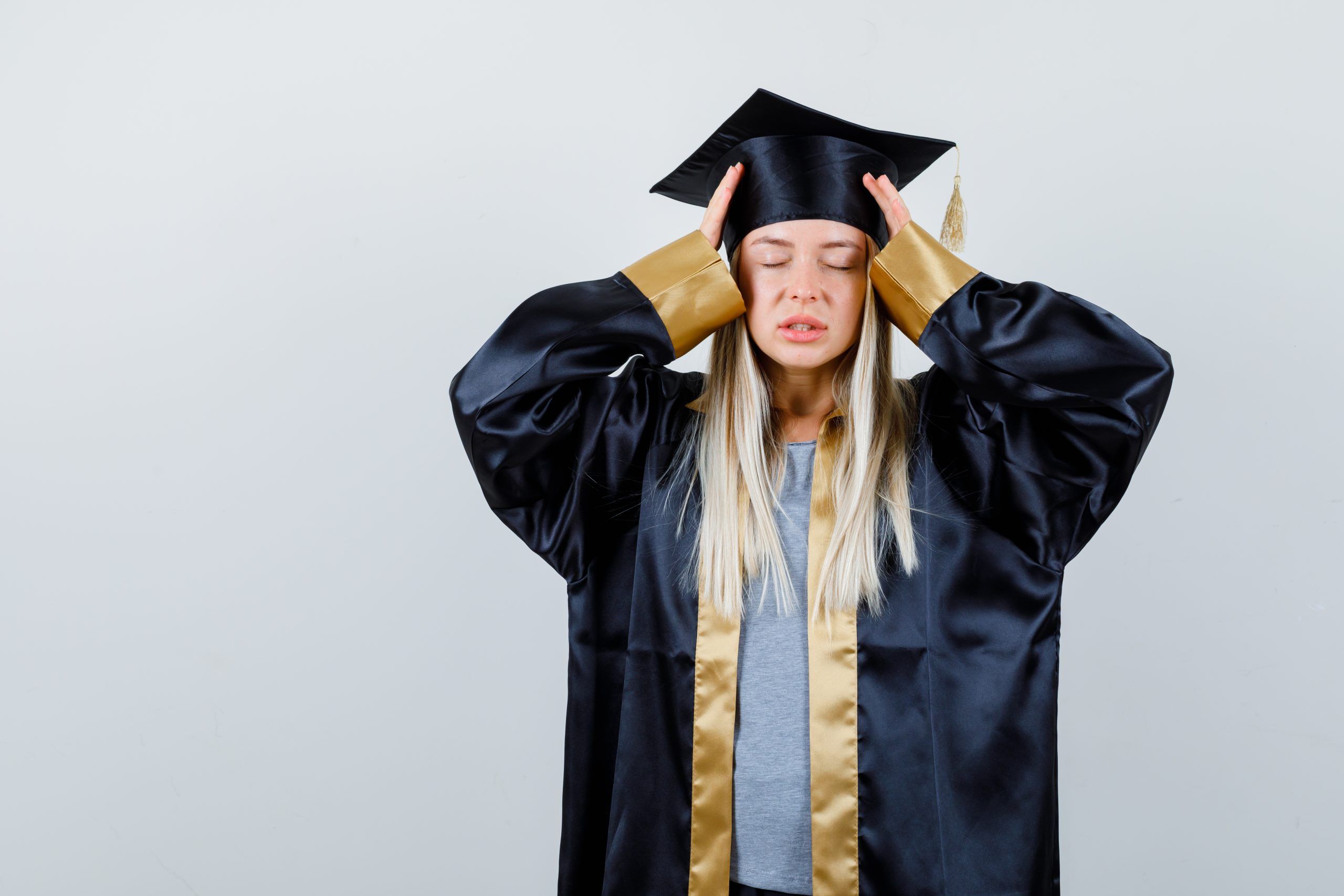 Mujer rubia vestida con una toga y birrete que acaba de graduarse y no sabe qué hacer.